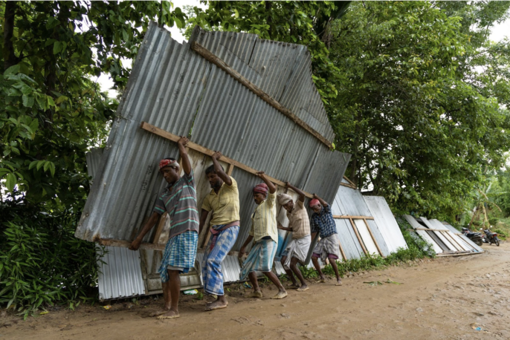 Residents of Chirakuta village carry dismantled roofs of their houses in Dhubri, Assam, on July 5. Photo: Kazi Sharowar Hussain