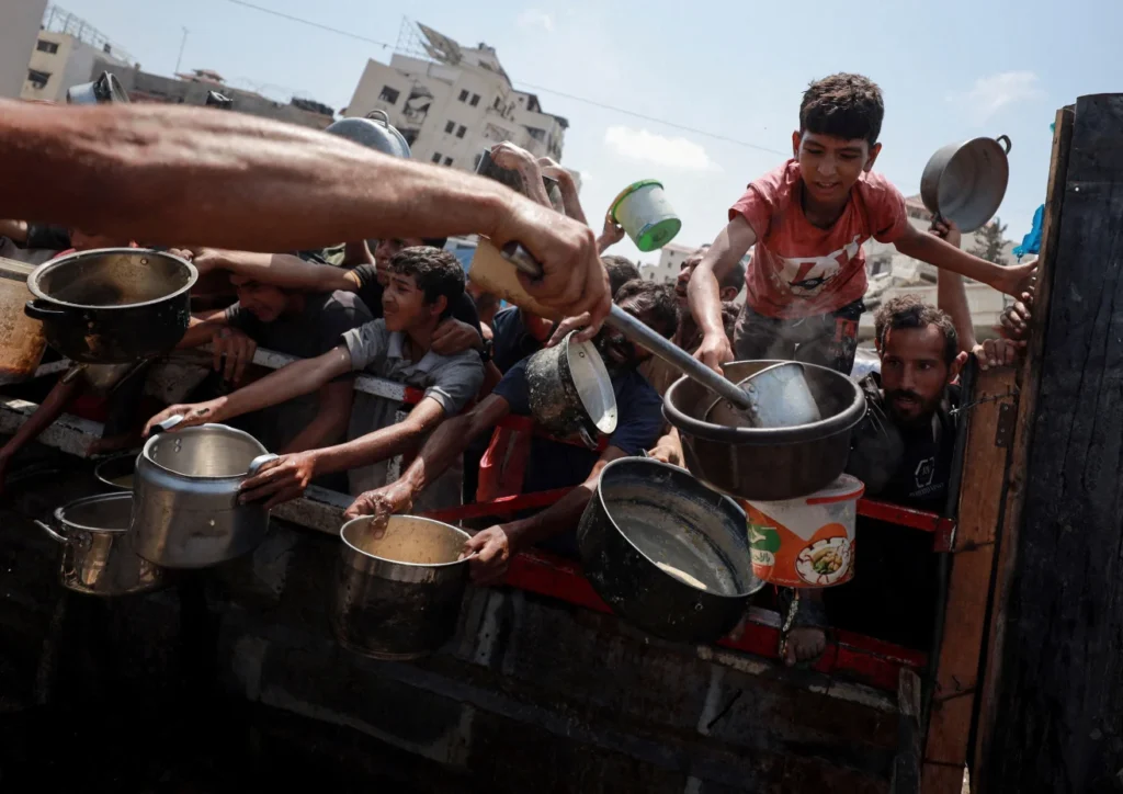 Palestinians gather to receive food from a charity kitchen amid a hunger crisis in Gaza City on Monday