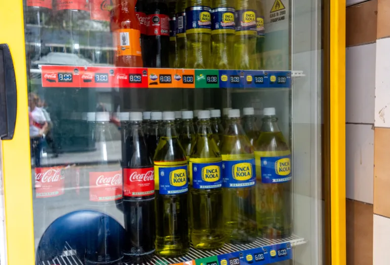Coca-Cola and Inca Kola bottles sit side by side in a store refrigerator in Lima