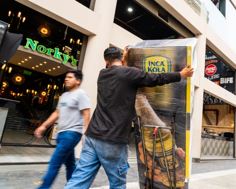 Workers deliver an Inca Kola machine to a business in Lima