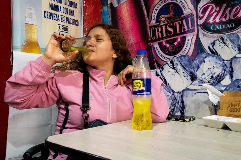 Food vendor Maria Sanchez enjoys an Inca Kola during lunch near Lima’s main square