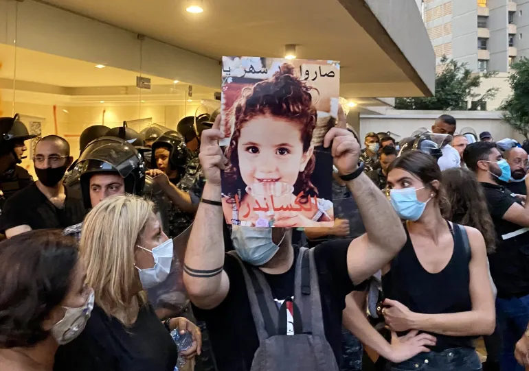 A protester holds up a picture of three-year-old Alexandra Naggear, who was killed in the Beirut port explosion
