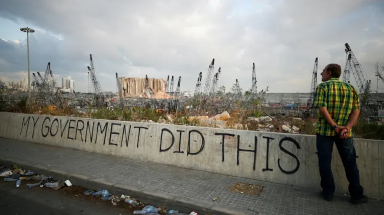A man stands near graffiti at the damaged port after the explosion. In Beirut on August 11, 2020