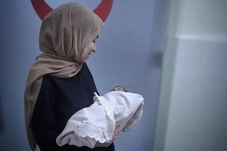 Nada Almadhoun holds a newborn she helped deliver on July 2