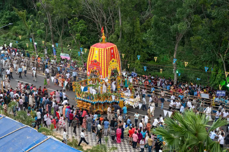 One of the three chariots being pulled by participants and organisers, while members of the public watch from behind barricades, on May 5, 2025