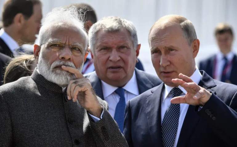 Russia’s President Vladimir Putin (R) speaks with India’s Prime Minister Narendra Modi (L) during a visit to the Zvezda shipyard, accompanied by Rosneft Russian oil giant chief Igor Sechin (C)