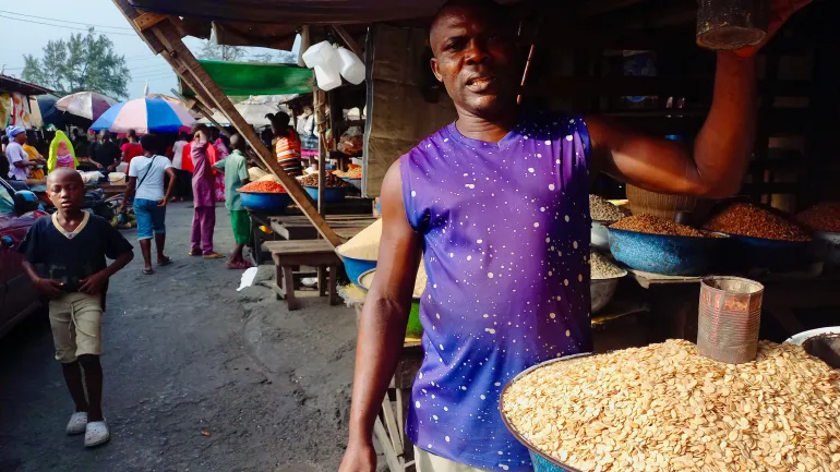 A salesman at the Idi Araba market in Lagos shows the cups he uses for measuring melon seeds