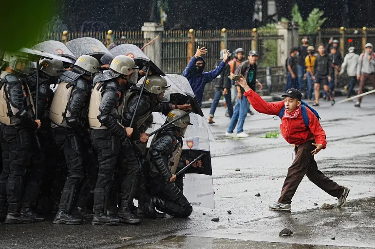 A protester throws a rock at riot police officers during a protest against lavish allowances given to parliament members, in Jakarta, Indonesia, on August 28, 2025