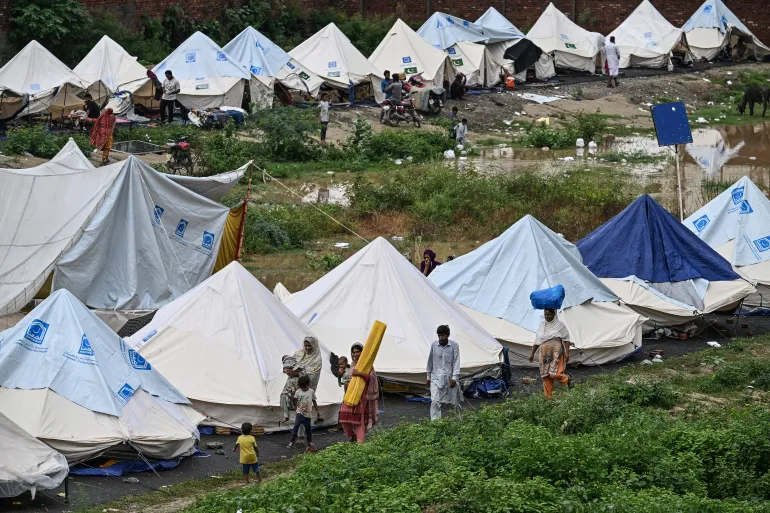 Flood-affected people walk along the shelters at a makeshift camp in Chung, in Pakistan’s Punjab province, on August 31, 2025. Nearly half a million people have been displaced by flooding in eastern Pakistan after days of heavy rain swelled rivers