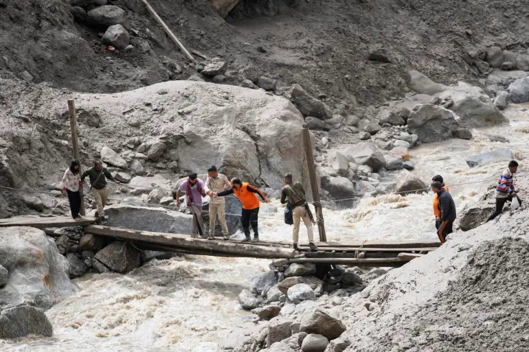 Stranded pilgrims cross a water channel using a makeshift bridge the day after flash floods in Chositi village, Kishtwar district, in Indian-administered Kashmir last month