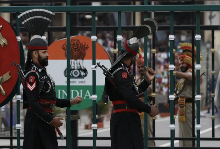 Pakistani, front, and Indian soldiers stand on their respective sides of their shared border during the flag-lowering ceremony in Wagah, Pakistan on May 4, 2025